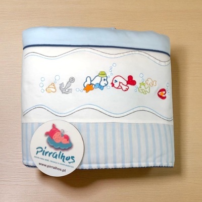 Manta azul e branca com peixes bordados e etiqueta da marca Pirralhos