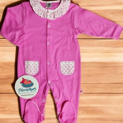 Macacão infantil rosa com gola e bolsos de bolinhas cor-de-rosa em branco sobre piso de madeira