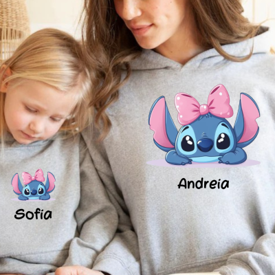 Criança e adulto com sweatshirts cinzentas e estampado de Stitch com laço cor de rosa, nomes Sofia e Andreia escritos.