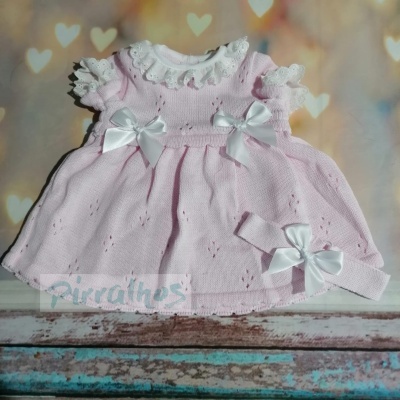 Vestido de bebé cor-de-rosa com laços brancos e renda, com fita combinando, fundo com corações desfocados
