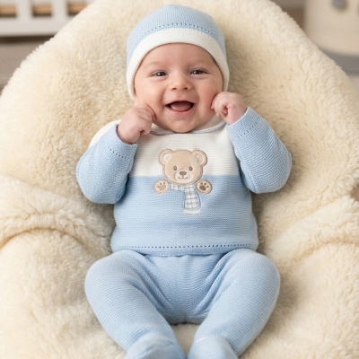 Bebé vestido de azul sentado num assento almofadado creme