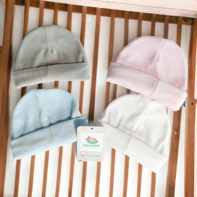 Quatro gorros de bebé em várias cores sobre uma superfície de madeira