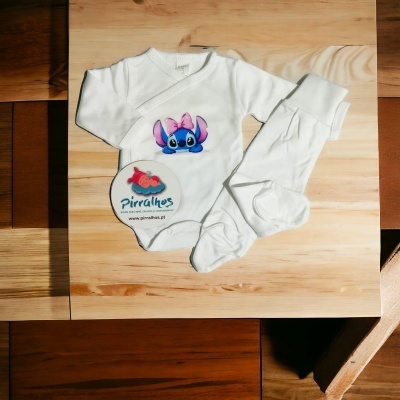 Conjunto branco de bebé com estampa de Stitch e etiqueta Pirralhos sobre madeira clara.