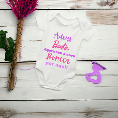 Body de bebé branco com texto rosa e roxo, flores cor-de-rosa e recorte roxo de chapéu de formatura