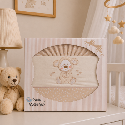Conjunto de roupa de bebé bege com ursinho bordado numa caixa sobre cómoda branca
