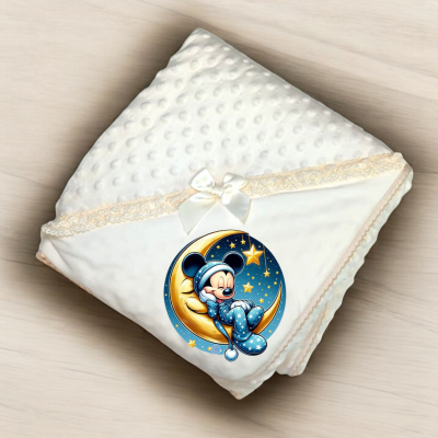 Manta branca com textura bolinha e borda de renda creme, com laço branco e imagem de Mickey Mouse em pijama azul sentado numa lua sobre fundo de estrelas.