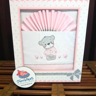 Conjunto para bebé com biberão e tecido rosa decorado com ursinho e flores, numa caixa branca com bolinhas cor de rosa.