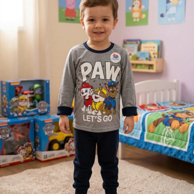 Menino com pijama da Patrulha Pata em quarto infantil com brinquedos e decoração temática.