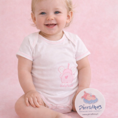 Bebé com body branco e rosa segurando círculo com logo Pirralhos sentado em fundo rosa