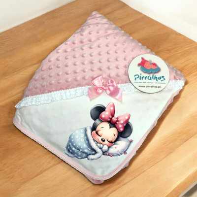 Cobertor infantil rosa e branco com estampa da Minnie Mouse sobre mesa de madeira