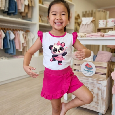 Menina em loja vestindo camisola branca com panda e saia cor-de-rosa.