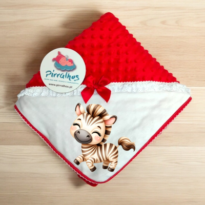 Manta de bebé vermelha e branca com etiqueta de marca Pirralhos sobre madeira clara