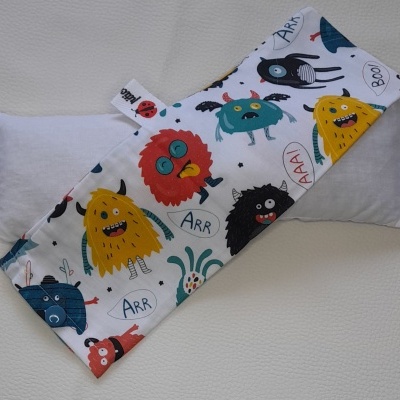 Almofada retangular para pescoço com tecido estampado de monstros coloridos.