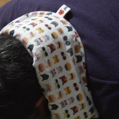 Faixa de tecido branco com estampas coloridas de cabeças de gatos no pescoço de pessoa de camisa roxa