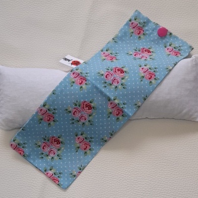 Almofada branca com capa azul clara com flores cor-de-rosa e bolinhas brancas