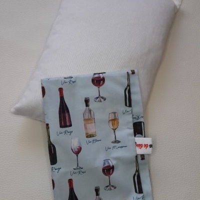 Almofada branca com capa azul com estampados de garrafas e copos de vinho