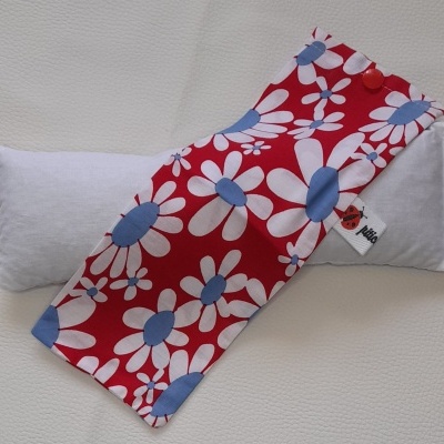 Almofada branca com capa estampada de flores brancas e azuis sobre fundo vermelho