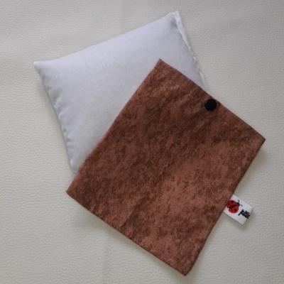 Almofada branca com capa castanha e etiqueta Héli sobre superfície clara