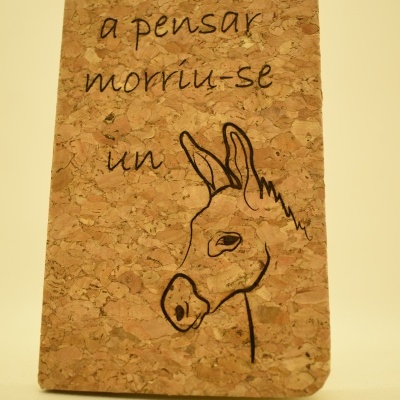 Capa de caderno de cortiça com desenho de burro e texto em português