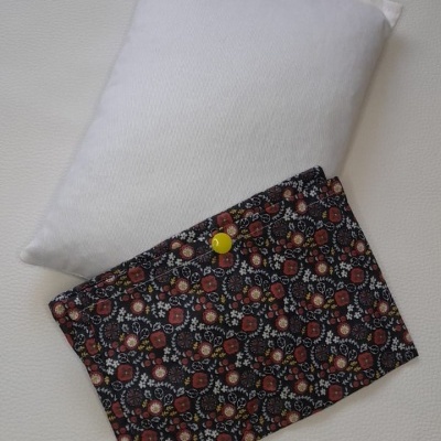 Almofada branca retangular com capa floral preta e botão amarelo