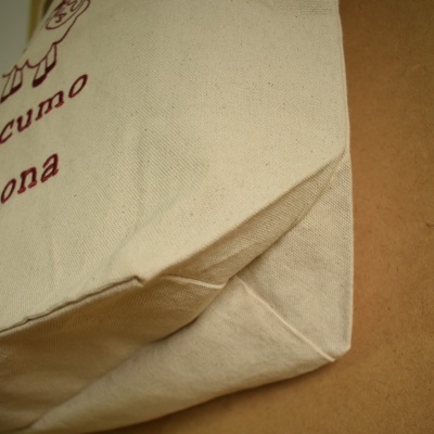 Bolsa de tecido cru com estampa vermelha, detalhe da parte inferior com fundo castanho