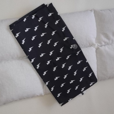 Almofada térmica preta com padrão branco de relâmpagos sobre almofada branca