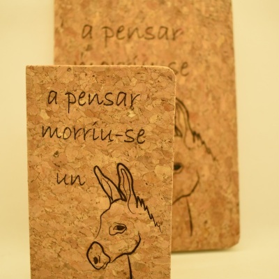 Dois cadernos de capa em cortiça com desenho de burro e texto em português.