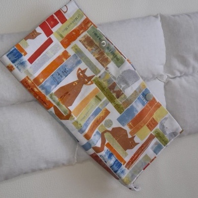 Duas almofadas, uma branca e outra com padrão de livros e gatos coloridos