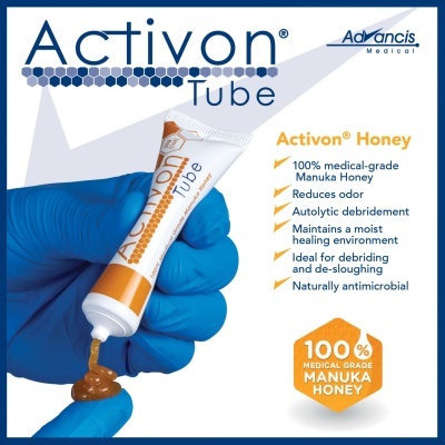 Mão com luva azul a espremer creme Activon Tube com mel Manuka