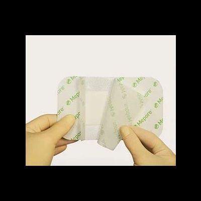 Curativo MePore em embalagem branca com texto verde, aberto por mãos com luvas.