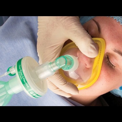 Máscara de oxigénio amarela e transparente a ser usada por uma pessoa com touca azul