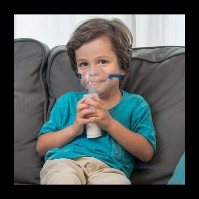 Criança com dispositivo de inalação sentado num sofá cinzento