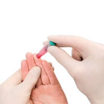 Mãos com luvas a usar lanceta para testar dedo