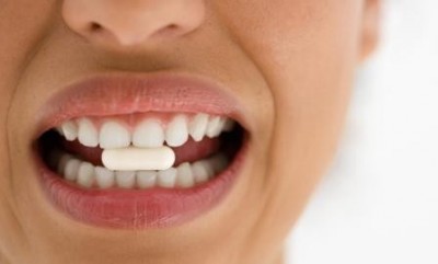 Boca com comprimido branco entre os dentes