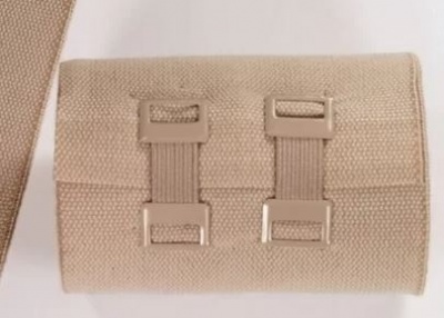 Carteira ou bolsa bege de tecido com presilhas retangulares e alça larga.