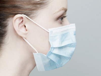 Máscara facial descartável azul clara usada por mulher.