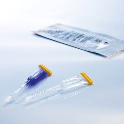 Dois aplicadores descartáveis transparentes com tampas amarelas sobre superfície branca