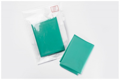 Capa ou saco plástico verde, embalado e aberto, sobre fundo branco