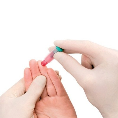 Mãos com luvas a usar lanceta para testar dedo