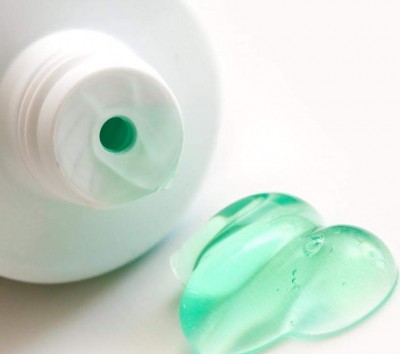Tubo branco com bico e gel verde claro em superfície branca