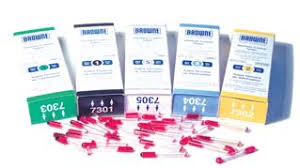 Caixas pequenas coloridas com agulhas com tampa vermelha sobre superfície branca com sombra azul