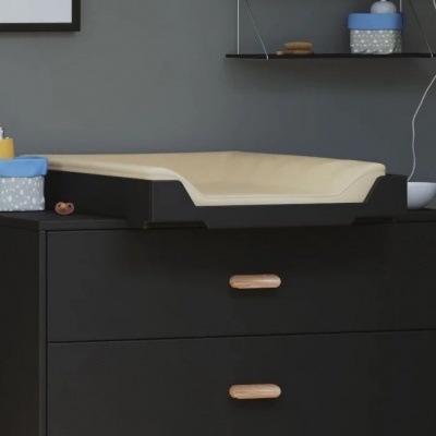 Muda-fraldas bege com laterais pretas sobre móvel preto com puxadores de madeira