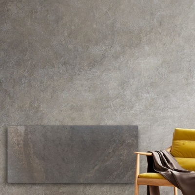 Radiador de parede rectangular em pedra cinzenta ao lado de uma cadeira amarela com manta cinzenta