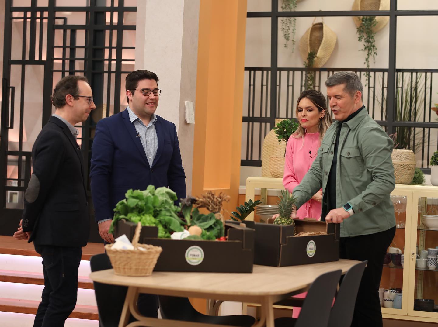 quatro pessoas em estúdio com caixas de frutas e legumes frescos numa mesa redonda