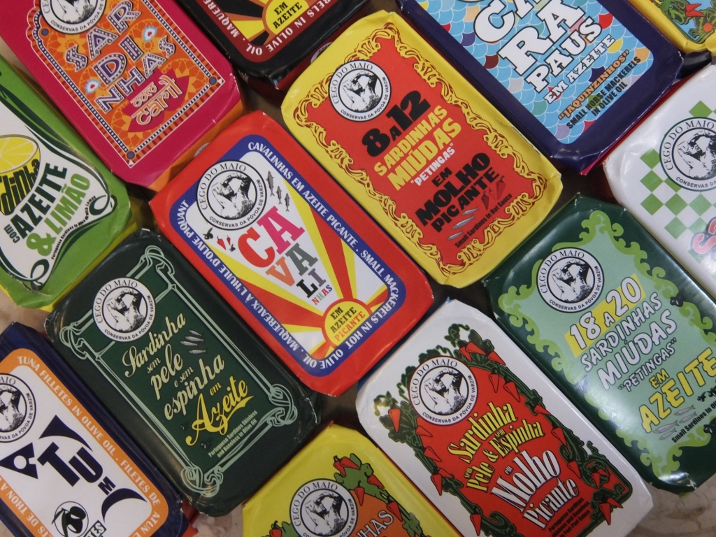 Latas coloridas de conservas com texto em português em disposição lado a lado