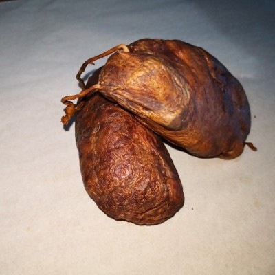 Duas chouriças secas castanhas sobre superfície clara