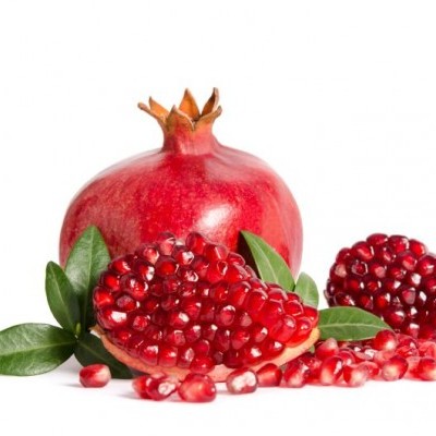 Romã inteira e cortada com sementes e folhas verdes