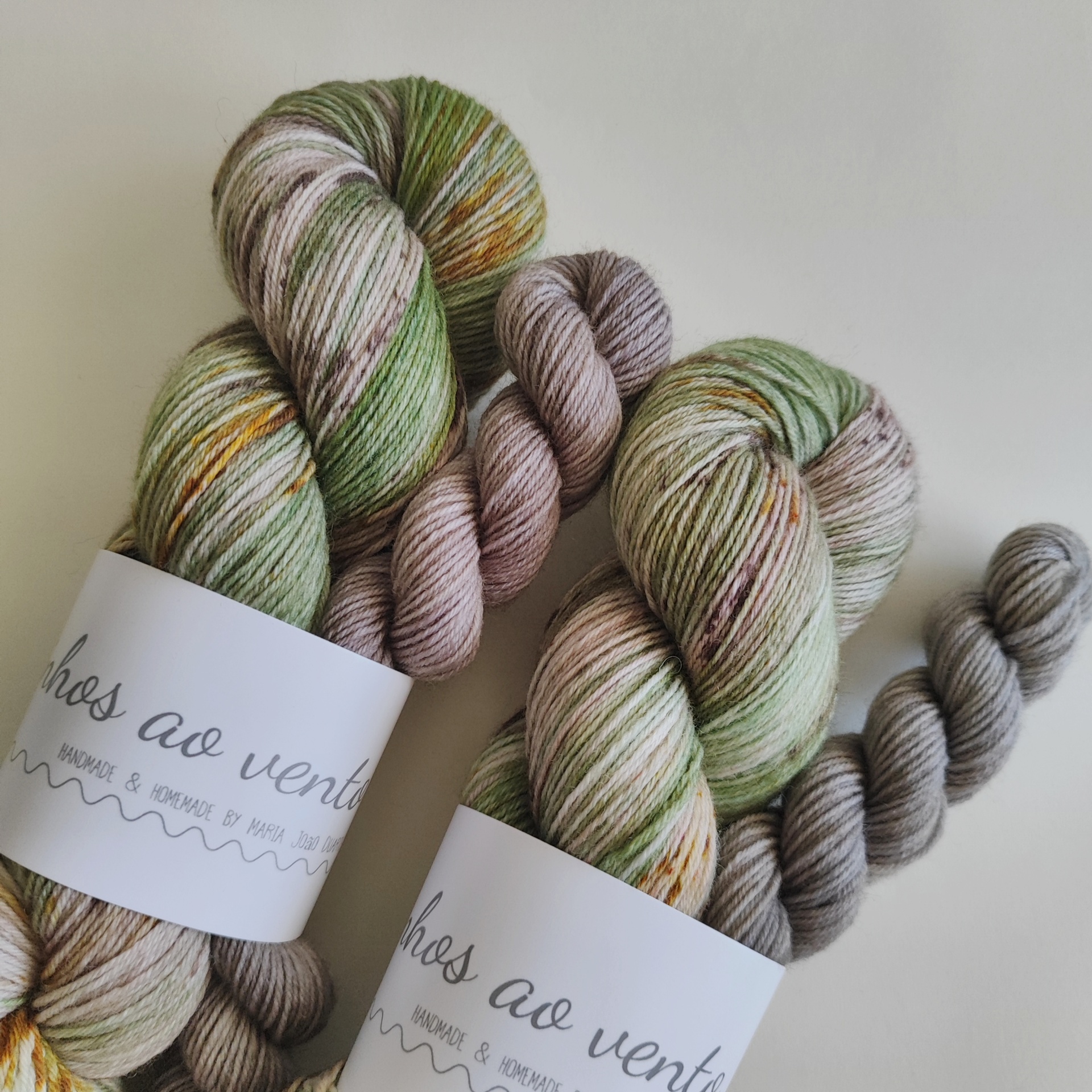 Mystery Sock Club Vários novelos de fios de lã em tons verdes e bege com etiquetas brancas