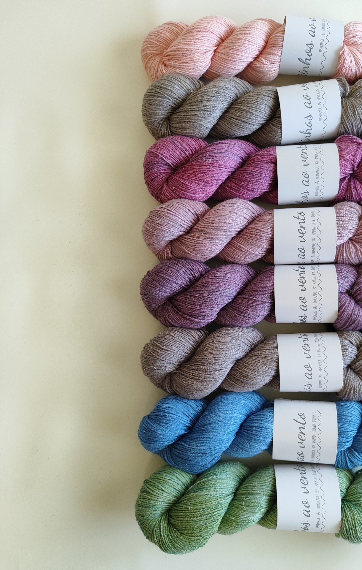 LINEN SILK - BY ORDER Oito novelos de fio colorido com etiquetas brancas alinhados