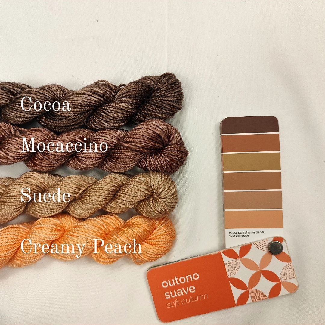 Quatro novelos de lã em tons castanhos e pêssego com paleta de cores e cartão 'outono suave'